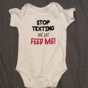 white onesie saying “stop texting and feed me”